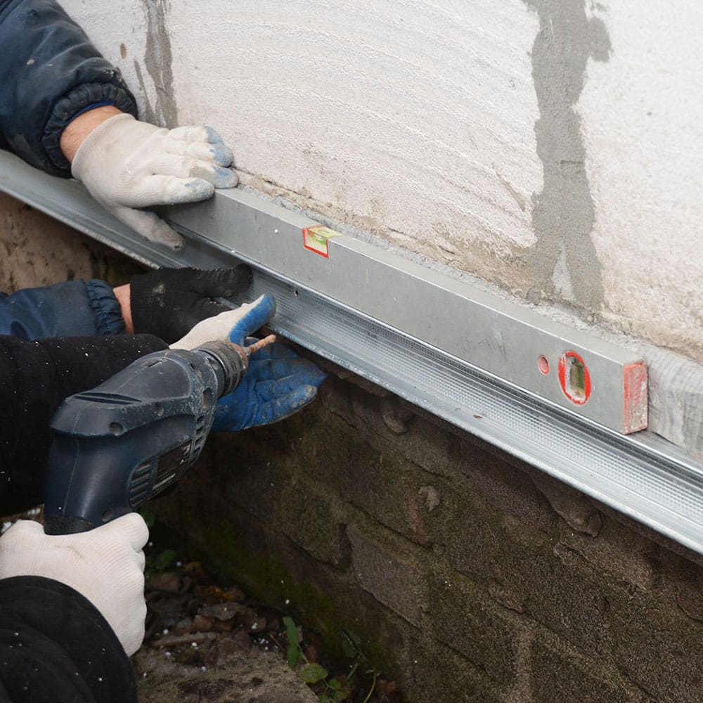 Foundation repair specialist assessing and waterproofing a home foundation