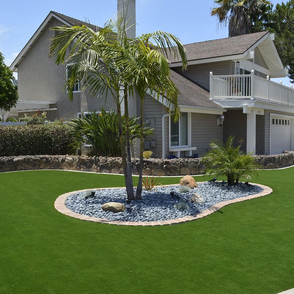 Artificial turf installer laying synthetic grass in a residential backyard