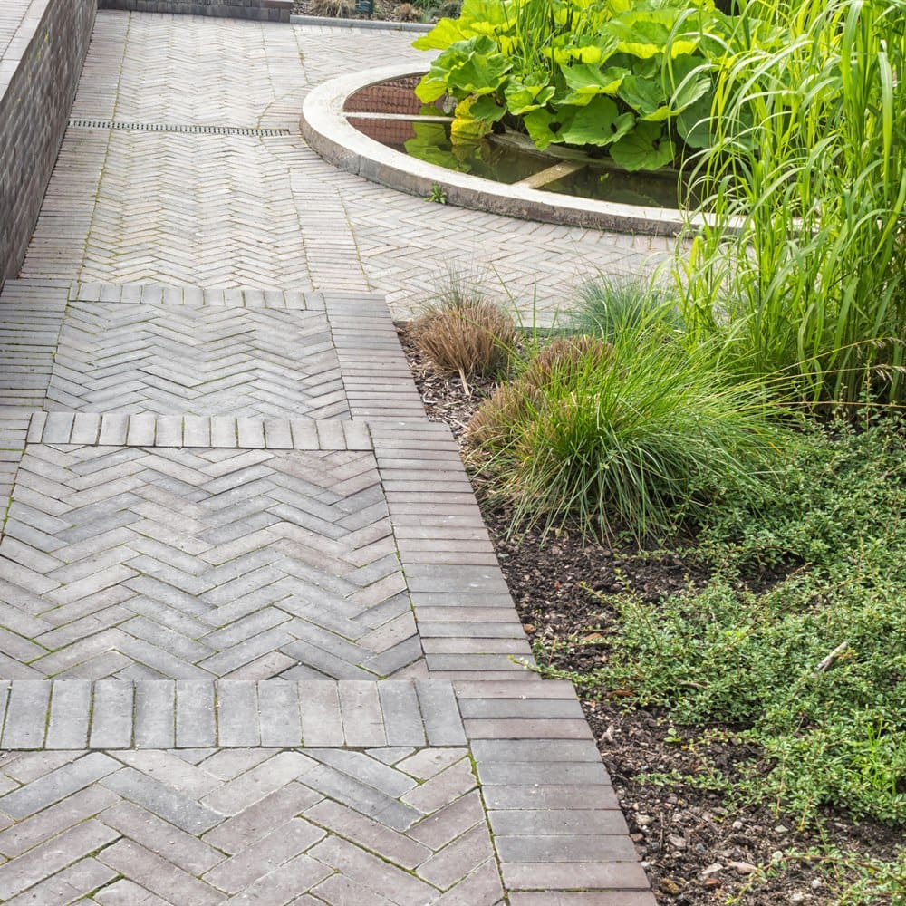 Brick pathway with pond and lush greenery