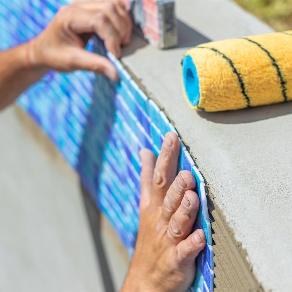 construction-worker-adds-tile-to-concrete-wall Construction worker adds tile to concrete wall