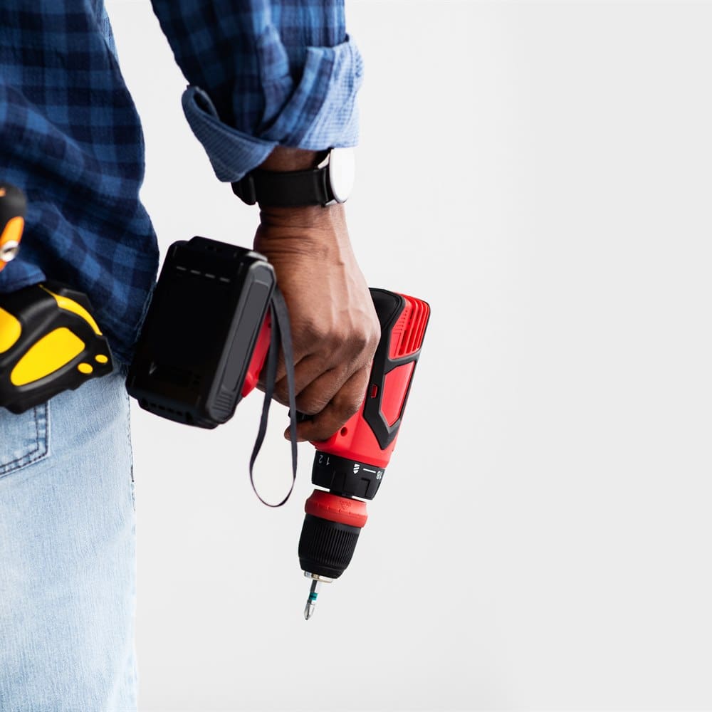 Construction worker holding drill wearing blue