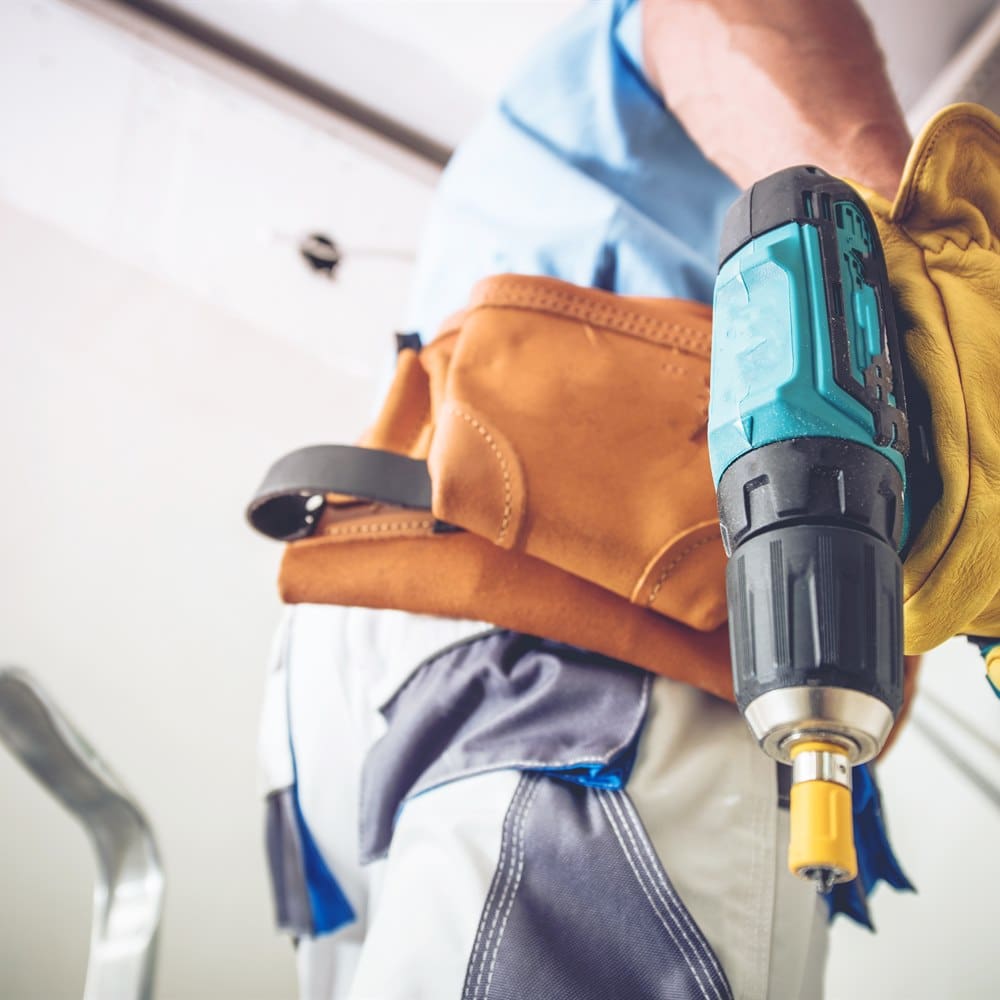 Construction worker holds drill with leather glove