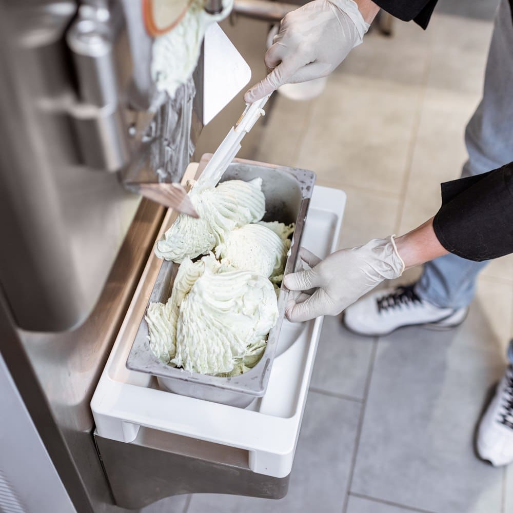 Dispensing soft serve ice cream into container