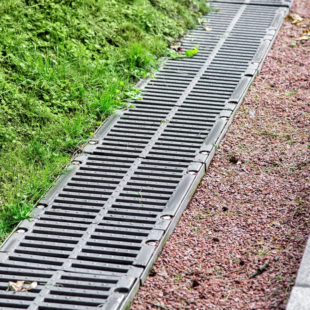 Drainage grate between greenery and gravel path