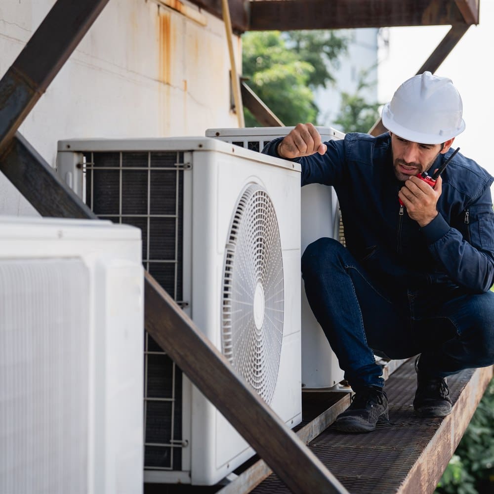 Hvac technician squatting and using walkie