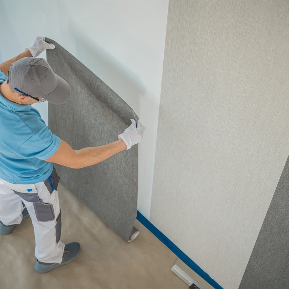 Man installing wallpaper in an interior space