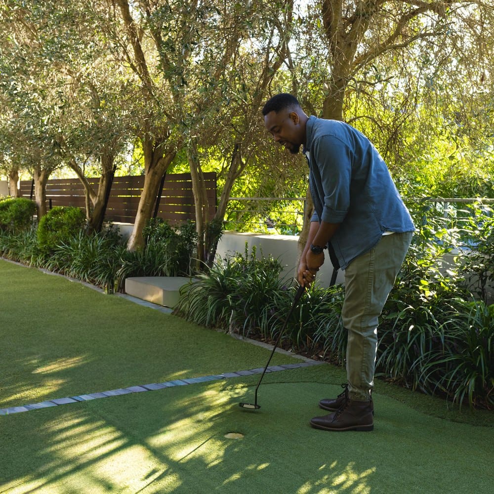 Man practicing golf putting on a backyard green