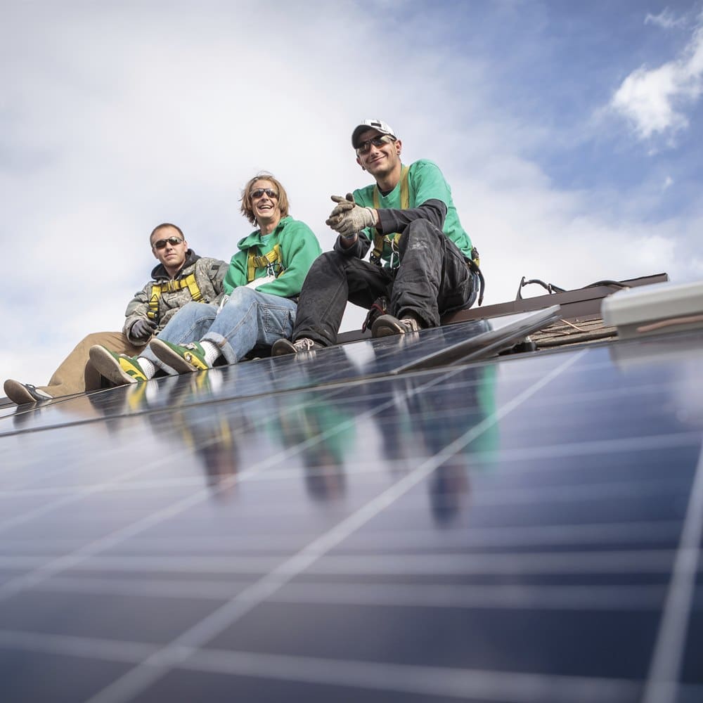 Solar panel installers sitting on rooftop array